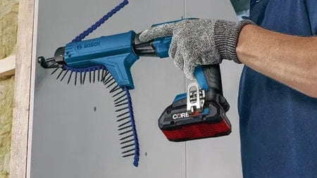 Person using Bosch GTB18V-45 screwgun with GMA22 auto-feed attachment to fasten screws into drywall. Tool features collated screw strip and CORE18V battery for cordless operation.