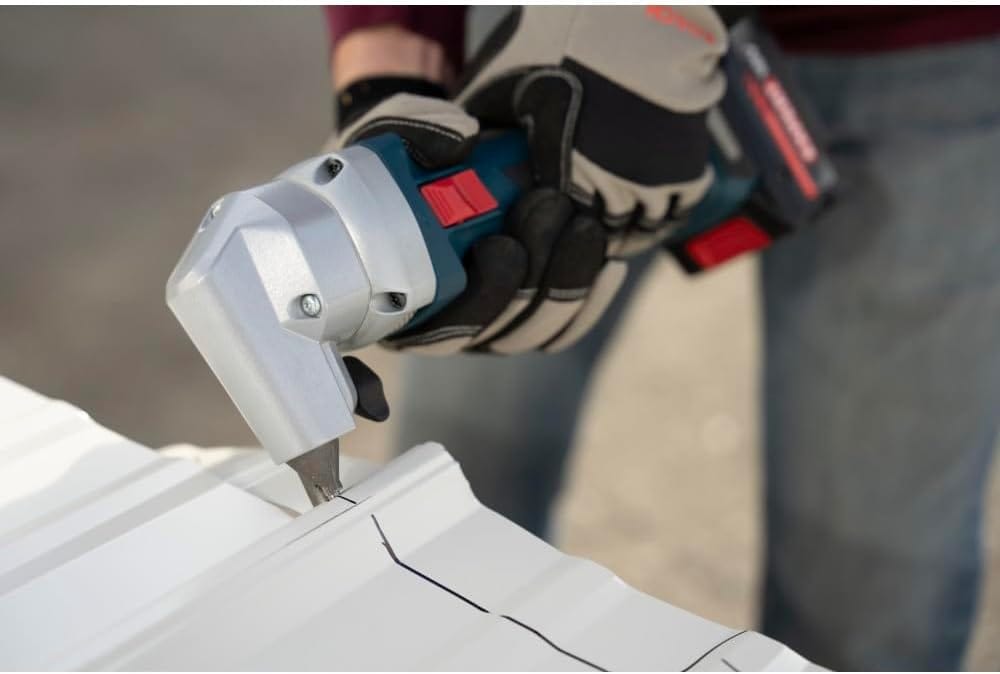 An action shot of a sheet metal worker wearing heavy-duty padded work gloves using the Bosch 18V cordless nibbler to punch a precise straight path across a ribbed white corrugated roofing panel along a pre-marked black marker guidance line.