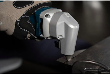 A close-up macro action shot focused on the rugged silver cast metal cutting head of the Bosch 18V nibbler as it punches a clean, burr-free linear seam directly into a heavy industrial sheet metal plate.