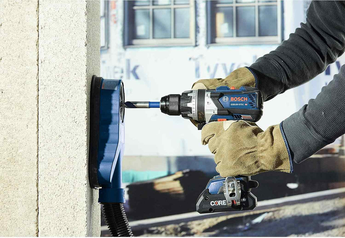 Action shot of a person using the hammer drill with a dust extraction system to drill into the side of a concrete building pillar.