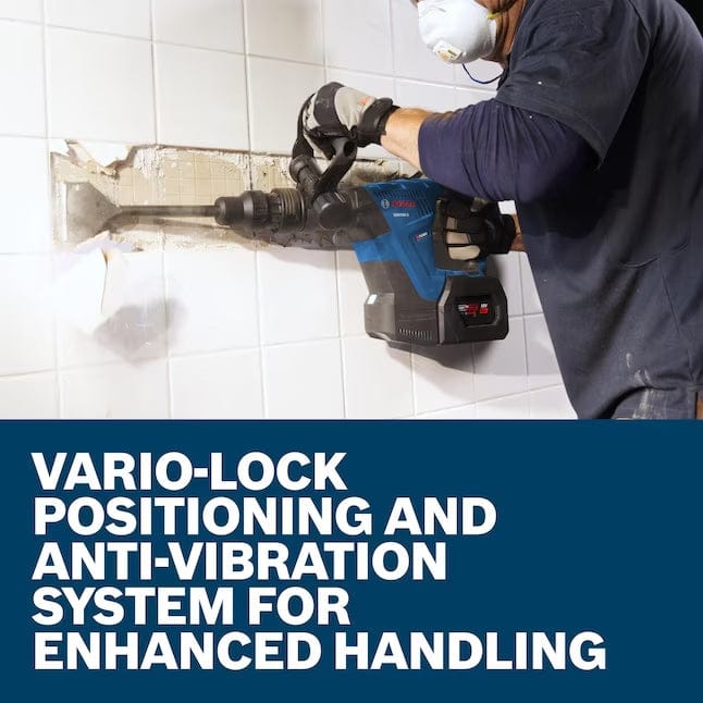 A worker wearing a face mask and gloves uses the Bosch demolition hammer horizontally to chip away at a tiled wall, illustrating the enhanced handling provided by the Vario-Lock and anti-vibration systems.