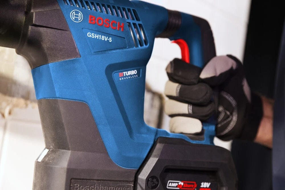 A close-up view of an operator's gloved hand gripping the rear handle of the Bosch GSH18V-5 demolition hammer, showcasing the BITURBO Brushless branding and AMPShare battery compatibility.