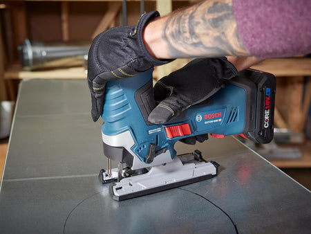Action shot of the Bosch jig saw being used to cut a circular pattern into a sheet of metal. The worker is wearing protective gloves and utilizing the barrel-grip for precise control during the curve cut.
