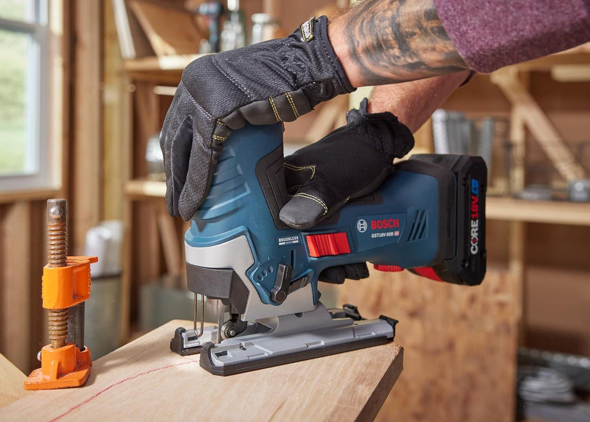 Action shot from a low angle showing the Bosch jig saw cutting through a thick piece of lumber. The worker uses the barrel-grip to stay close to the workpiece for enhanced precision.