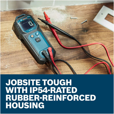 The Bosch GVT600-13 Digital Volt Meter resting on a wooden countertop next to an open outlet receptacle installation. The tool is connected to its premium red and black replaceable test leads with the screen displaying a baseline reading, set above a text banner reading Jobsite tough with IP54-rated rubber-reinforced housing.