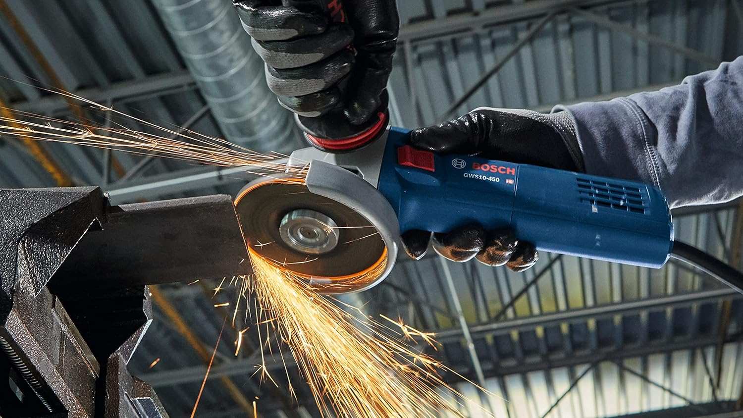 A close-up action shot of a worker using the grinder on metal, creating a stream of orange sparks.