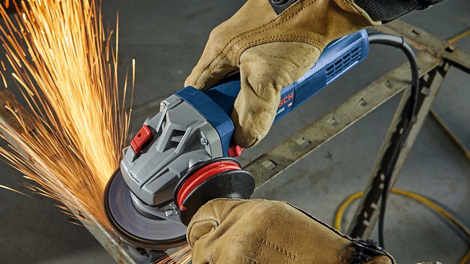 A professional wearing leather work gloves using the grinder to smooth a metal edge, generating sparks.