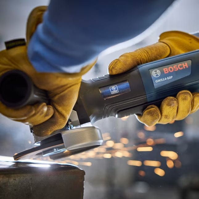 Close-up action shot of an operator using the Bosch GWS14-50P angle grinder to grind a metal surface, showing the KickBack Control logo on the tool and bright sparks being produced.