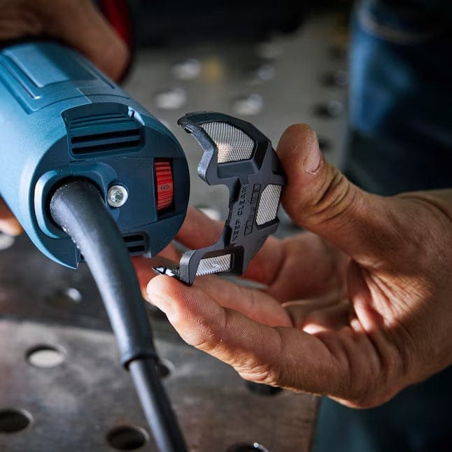 Close-up view of a person’s hands holding a black mesh dust filter near the rear air intake and variable speed dial of the Bosch corded angle grinder.