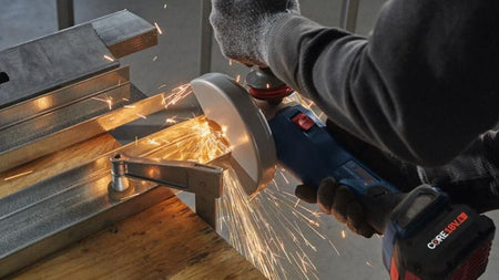 Close-up action shot of the Bosch GWS18V-13C angle grinder cutting through a metal wall stud, showcasing the high-torque performance and industrial-grade cutting speed of the BITURBO motor.
