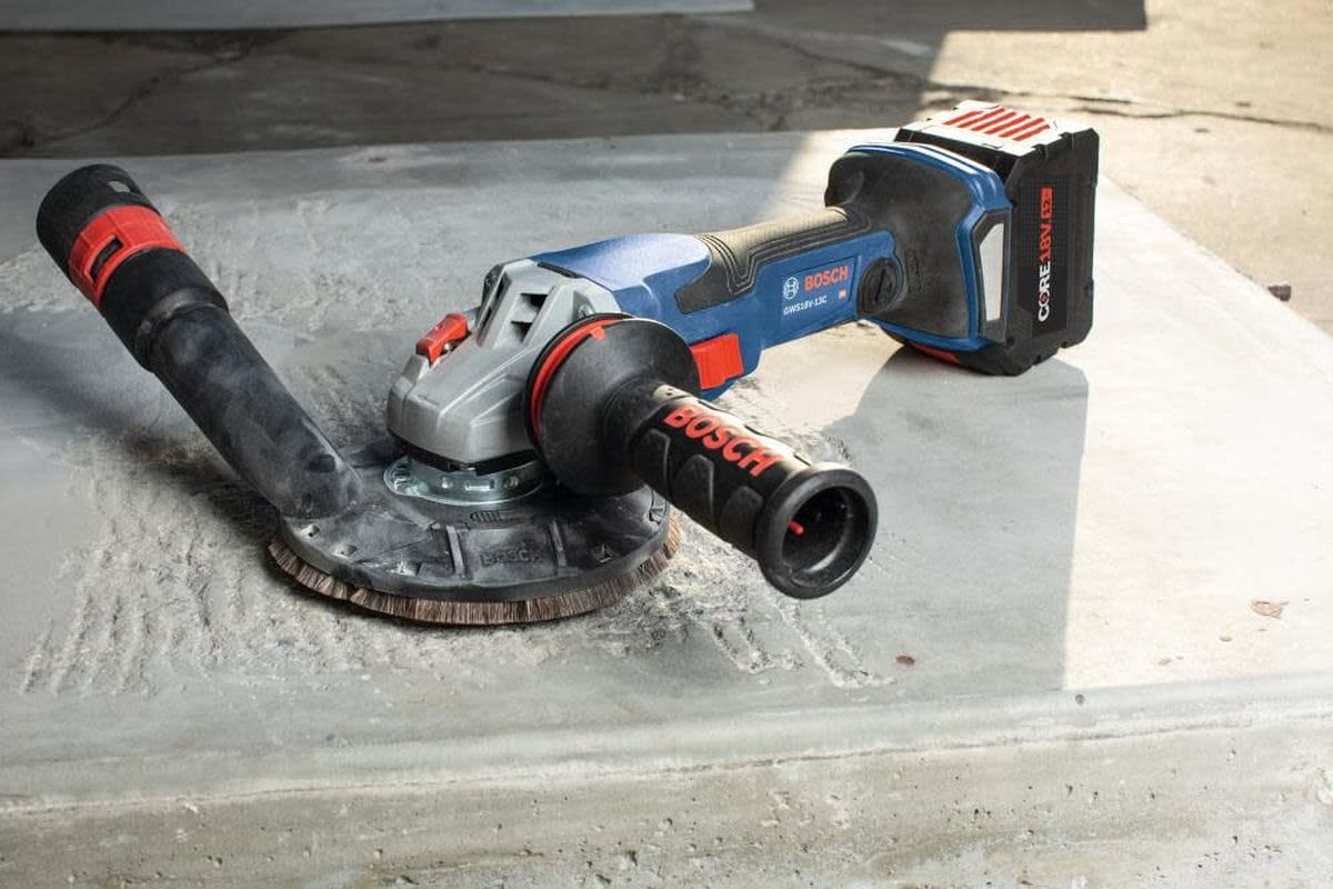 The Bosch PROFACTOR 18V angle grinder fitted with a professional surface grinding shroud and a diamond cup wheel, shown resting on a concrete surface prepared for industrial finishing.