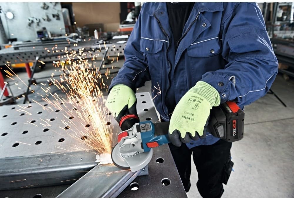 Individual using Bosch cordless angle grinder to grind metal on perforated workbench; sparks and safety gloves visible.
