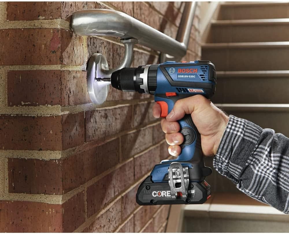 An action shot of a worker using the Bosch 18V hammer drill to secure a metal handrail bracket into a brick wall using the tool's high-torque driving capability.