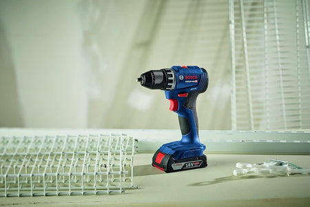 The Bosch GSR18V-400 18V compact brushless 1/2 inch drill driver standing upright on its 2Ah battery on a work surface, surrounded by white wire shelving brackets and hardware ready for a home organization project.