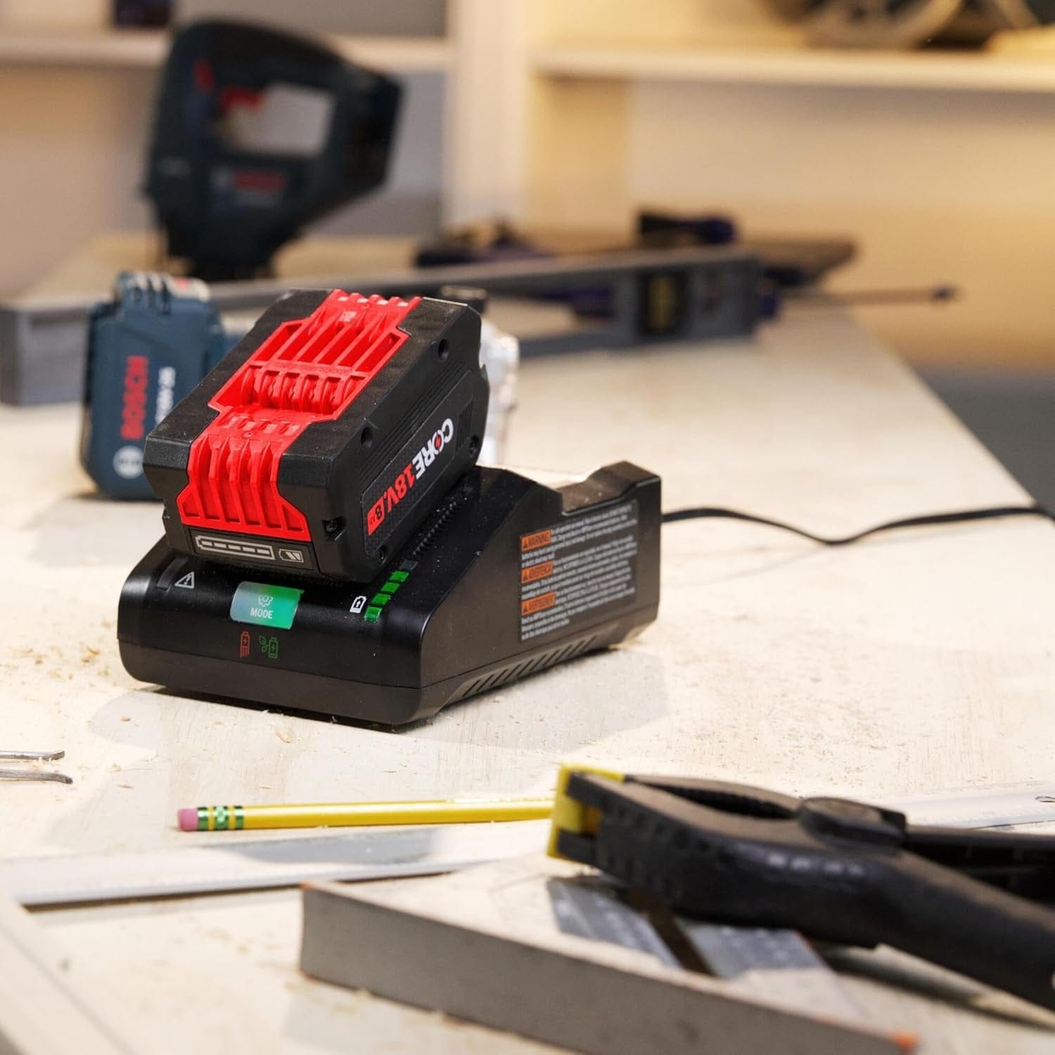 A Bosch CORE18V 8.0 Ah battery charging on the turbo fast charger on a workbench, with hand tools and power tools visible in the blurred background.