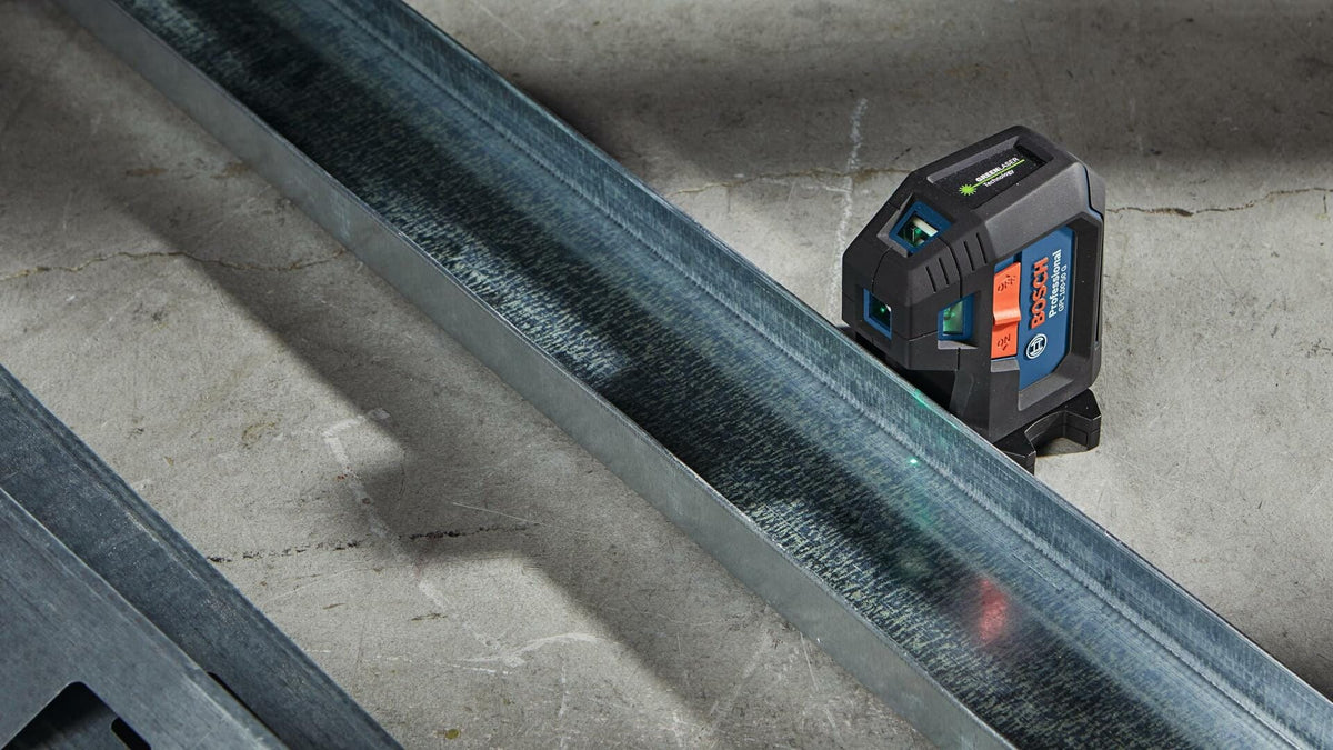 Action shot showing the Bosch GPL100-50G laser sitting on the ground, projecting the green level line along a steel stud floor track for construction layout