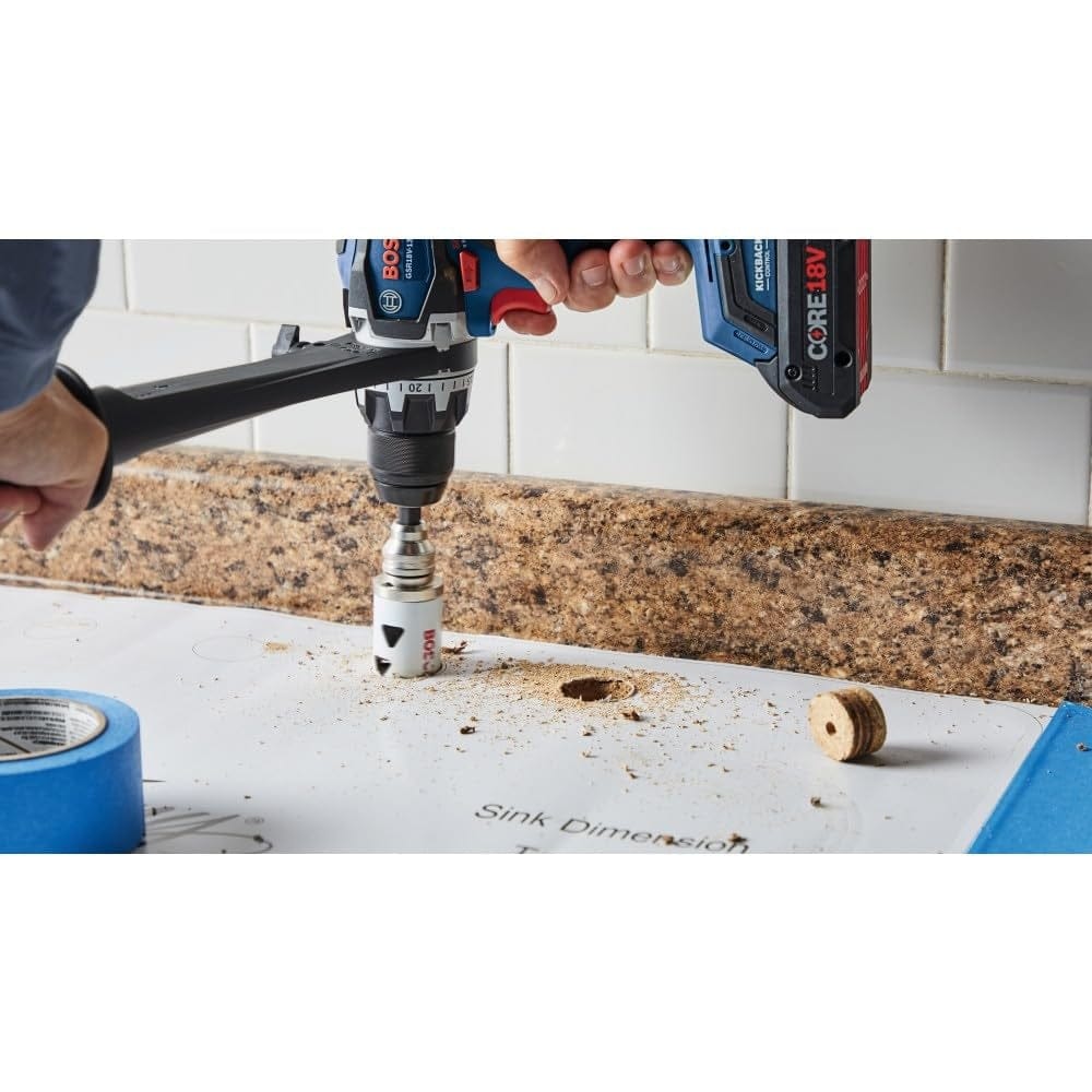 A contractor uses a cordless drill and hole saw to cut a hole in a white countertop surface over a sink template.