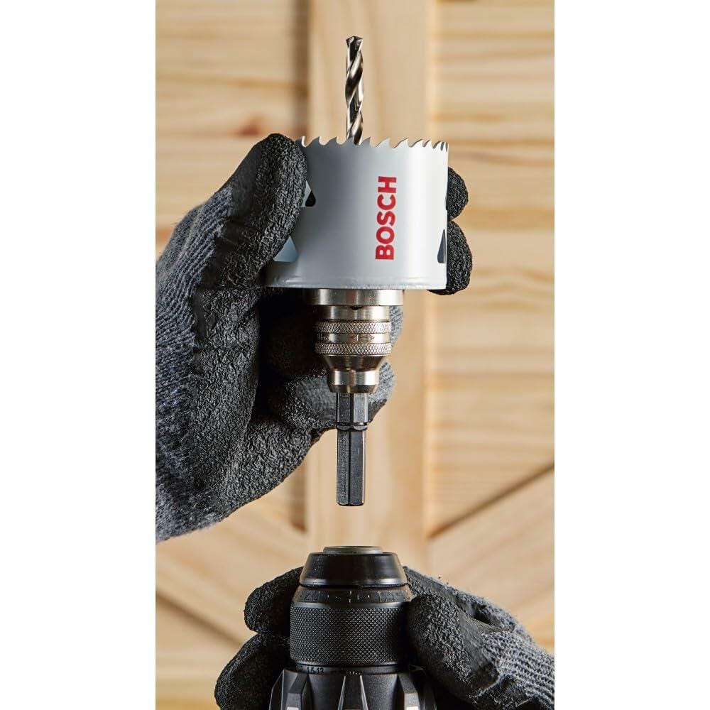 A person wearing work gloves is shown inserting the arbor of a Bosch bi-metal hole saw into the chuck of a cordless drill.