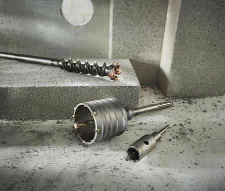Studio arrangement of various Bosch concrete drilling accessories including a large SDS-max core bit with the HC88 centering pin installed, alongside other bits on a concrete block.