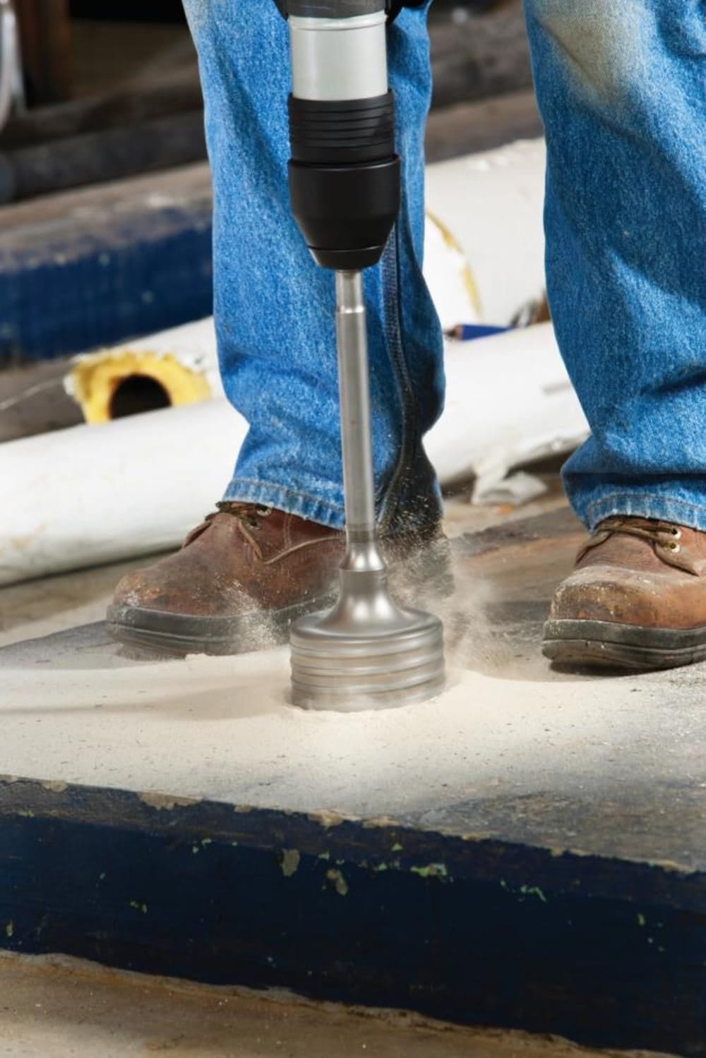 Close-up action shot of a core bit with the centering pin effectively drilling into a concrete slab, creating dust and debris.