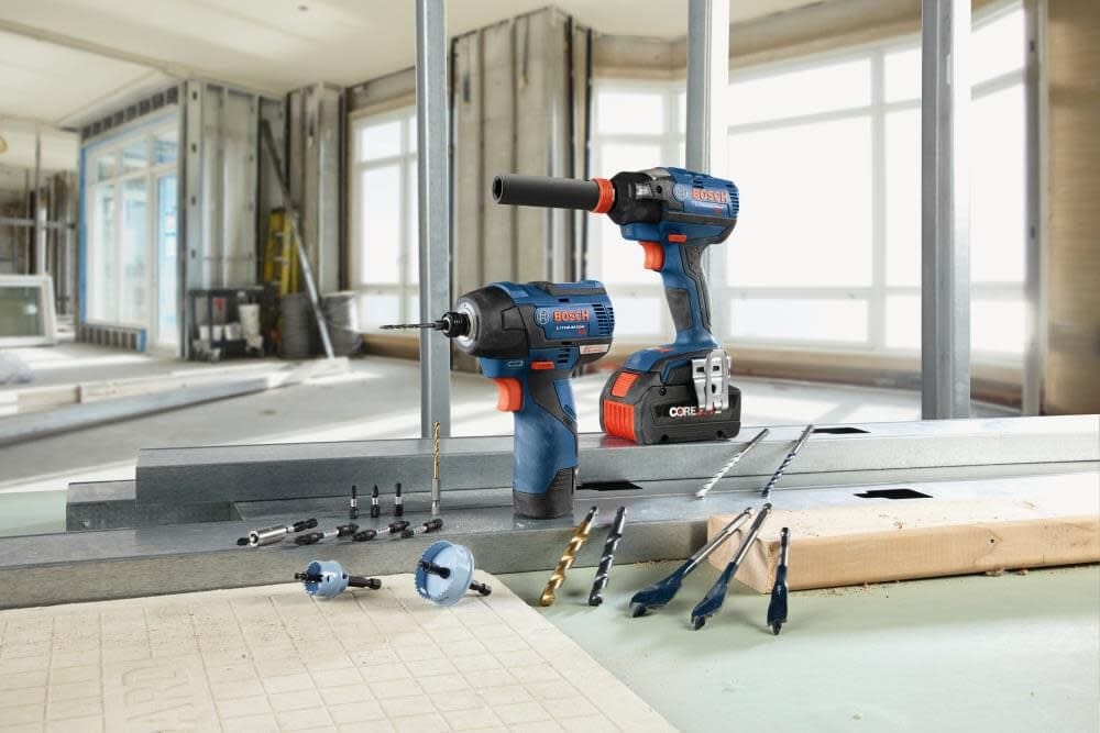 Lifestyle shot of Bosch cordless tools and various accessories including the drill bit arranged on a job site floor.