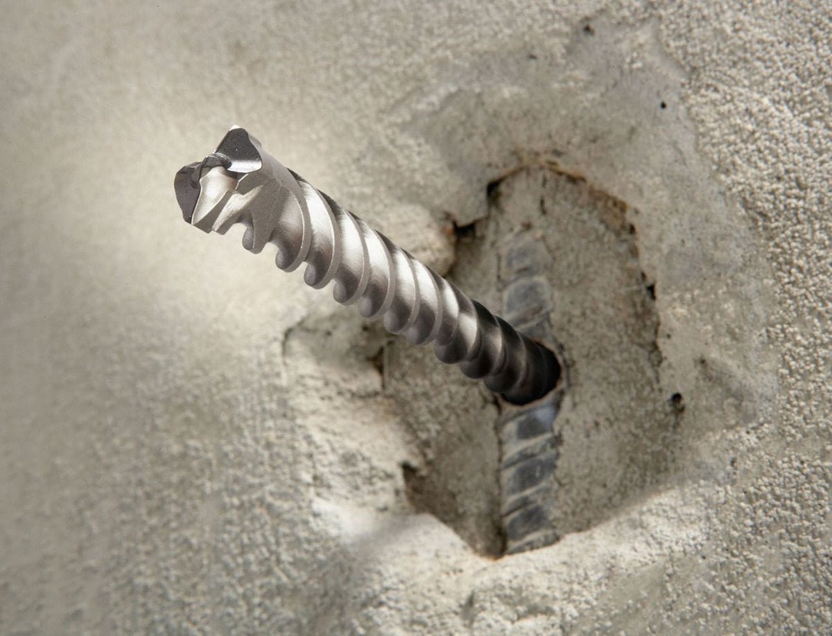 An action shot showing a Bosch Bulldog Xtreme rotary hammer bit boring into a concrete wall and successfully cutting through a buried piece of metal rebar.