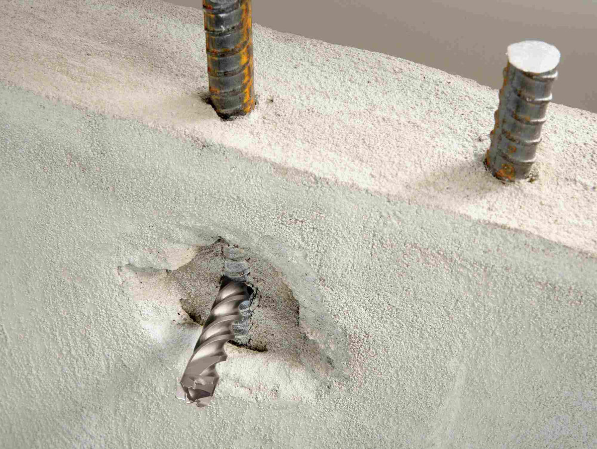 A close-up action shot showing the Bosch Bulldog Xtreme drill bit piercing through concrete and making direct contact with vertical rebar supports without stalling.