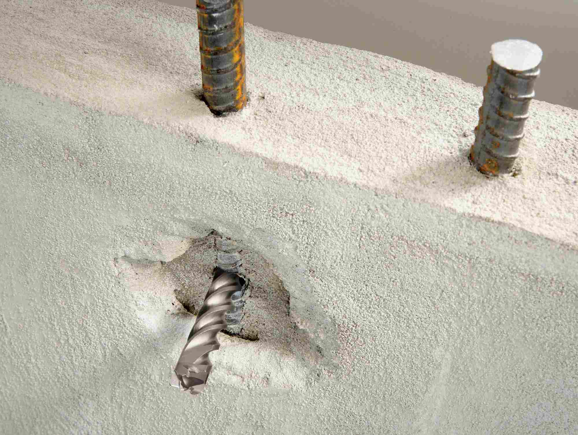 A close-up action shot showing the Bosch Bulldog Xtreme drill bit piercing through concrete and making direct contact with vertical rebar supports without stalling.