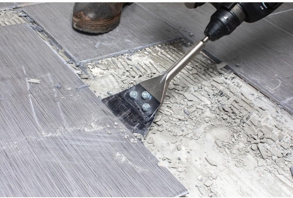 An action shot of the Bosch Bulldog floor scraper in use, demonstrating the sharp steel blade's ability to efficiently peel up ceramic floor tiles and hardened thinset from a concrete subfloor.