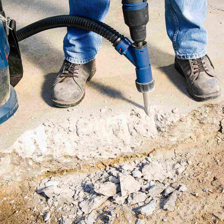 An action shot of a professional contractor using the Bosch SDS-max bull point chisel with a rotary hammer and dust extraction attachment to break through a thick concrete slab.