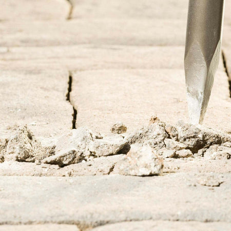 A detailed close-up of the Bosch R-Tec bull point tip fracturing a concrete surface, demonstrating the high-energy reflection technology that increases breakout efficiency and reduces user vibration.