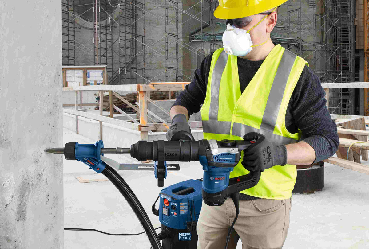 Professional construction worker using a Bosch SDS-Max rotary hammer, which is compatible with the 25-inch floor scraper blade, for heavy-duty concrete demolition.