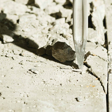 A high-impact perspective of the Bosch 16-inch star point chisel bit penetrating a concrete surface, showcasing the self-sharpening twist flutes that prevent binding during aggressive demolition.