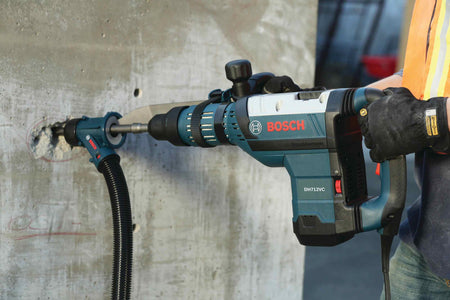 Close-up of a professional using a Bosch rotary hammer with a dust extraction attachment and the HS1936 SDS-Max R-Tec chisel bit to break into a solid concrete wall.