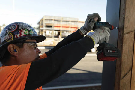 A jobsite application shot of a contractor utilizing the high-torque Bosch IDH182 impact driver for exterior metal siding installation, demonstrating the tool's compact power and ergonomic handling.