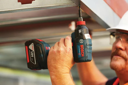A contractor using the Bosch IDH182 impact driver with a screwdriver bit to fasten metal components, demonstrating the high-torque performance and precise control of the EC Brushless motor.