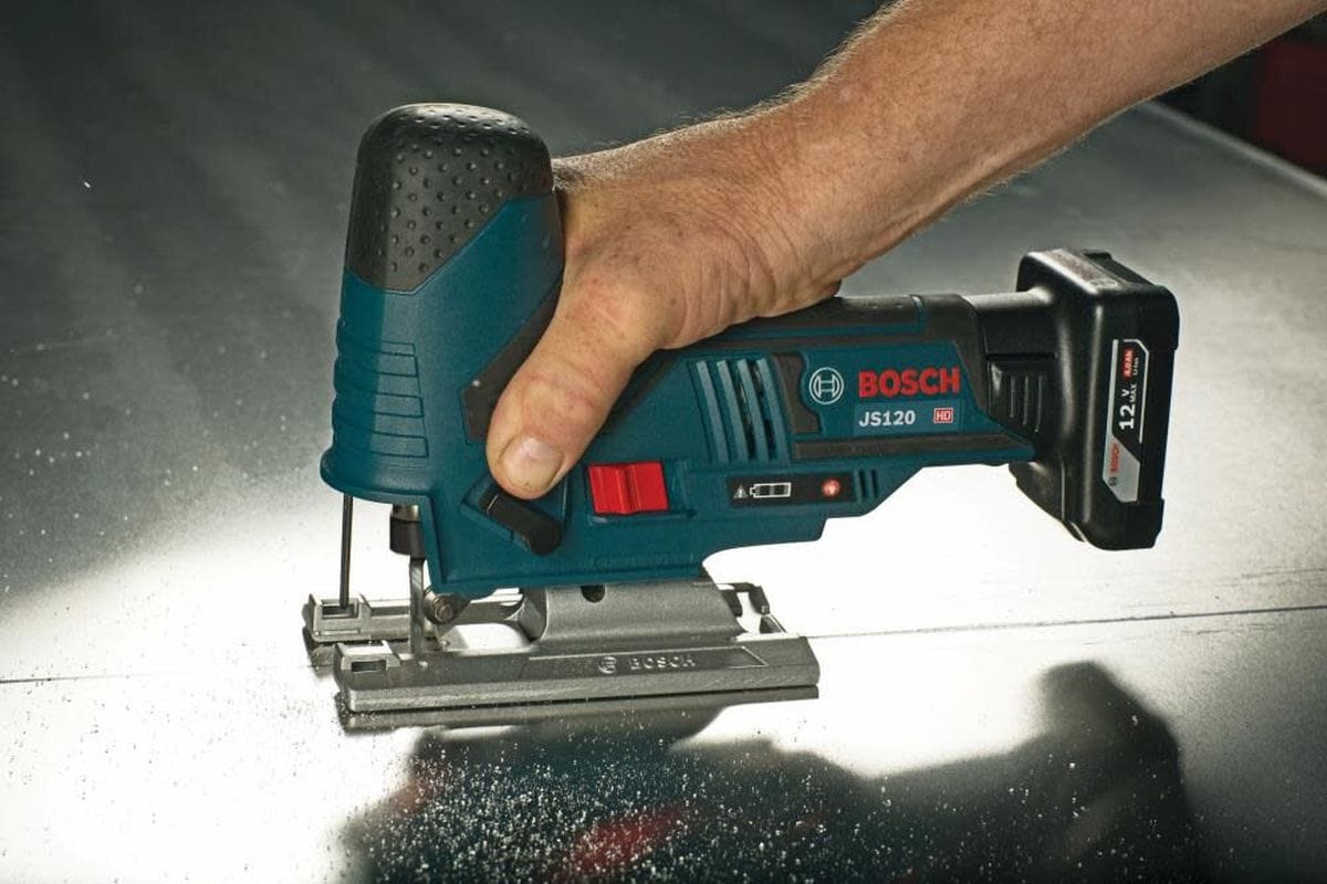 A professional using the Bosch barrel grip jig saw to cut through a metal sheet, showcasing the tool's versatility for both wood and aluminum applications with the appropriate T-shank blade.
