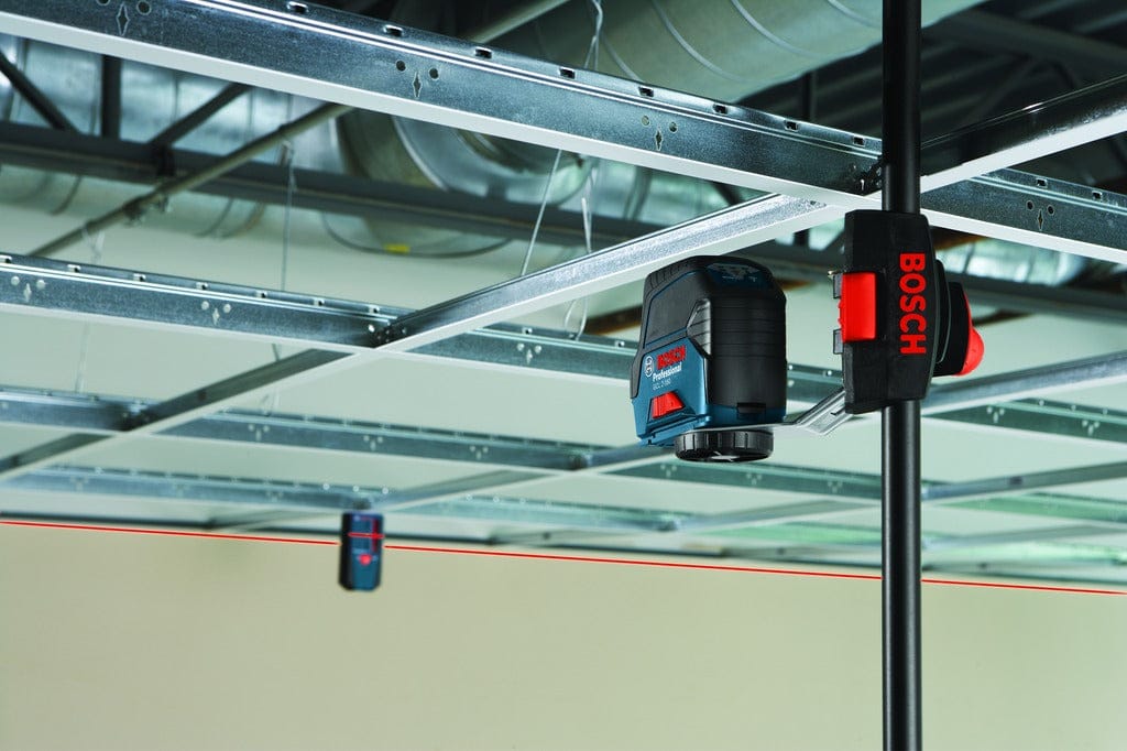 The Bosch LR6 receiver in use on a jobsite, catching a red beam from a pole-mounted Bosch GCL 2-160 cross-line laser for accurate layout across a long distance.
