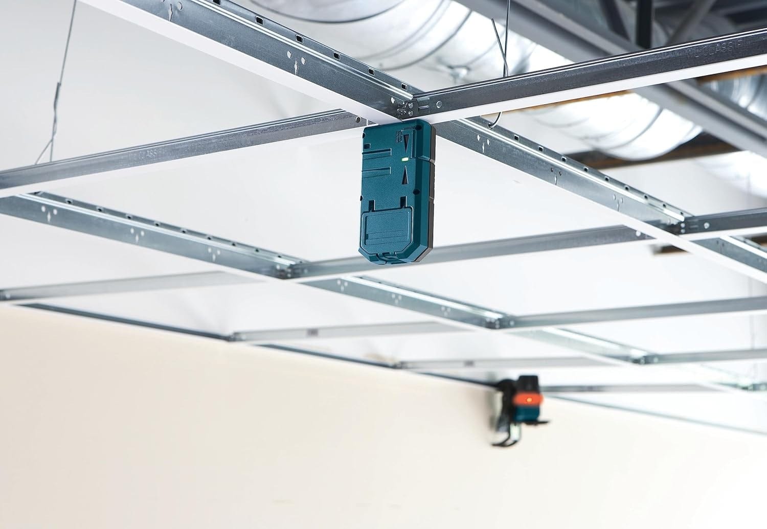 A Bosch LR6 laser receiver magnetically secured to a suspended ceiling grid, demonstrating its utility for hands-free interior leveling and installation.