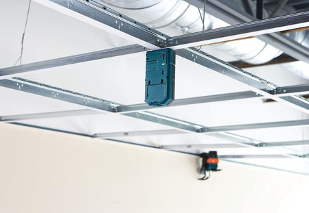 A Bosch LR6 laser receiver magnetically secured to a suspended ceiling grid, demonstrating its utility for hands-free interior leveling and installation.