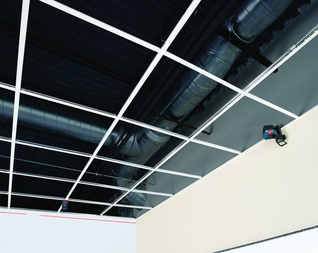 Wide view of an interior construction site showing a Bosch laser level and the LR6 receiver being used together to align a large-scale drop ceiling installation.