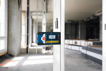 A professional using the Bosch LR8 digital detector magnetically mounted to a metal wall stud to verify the exact height of a red laser line in a commercial construction setting.