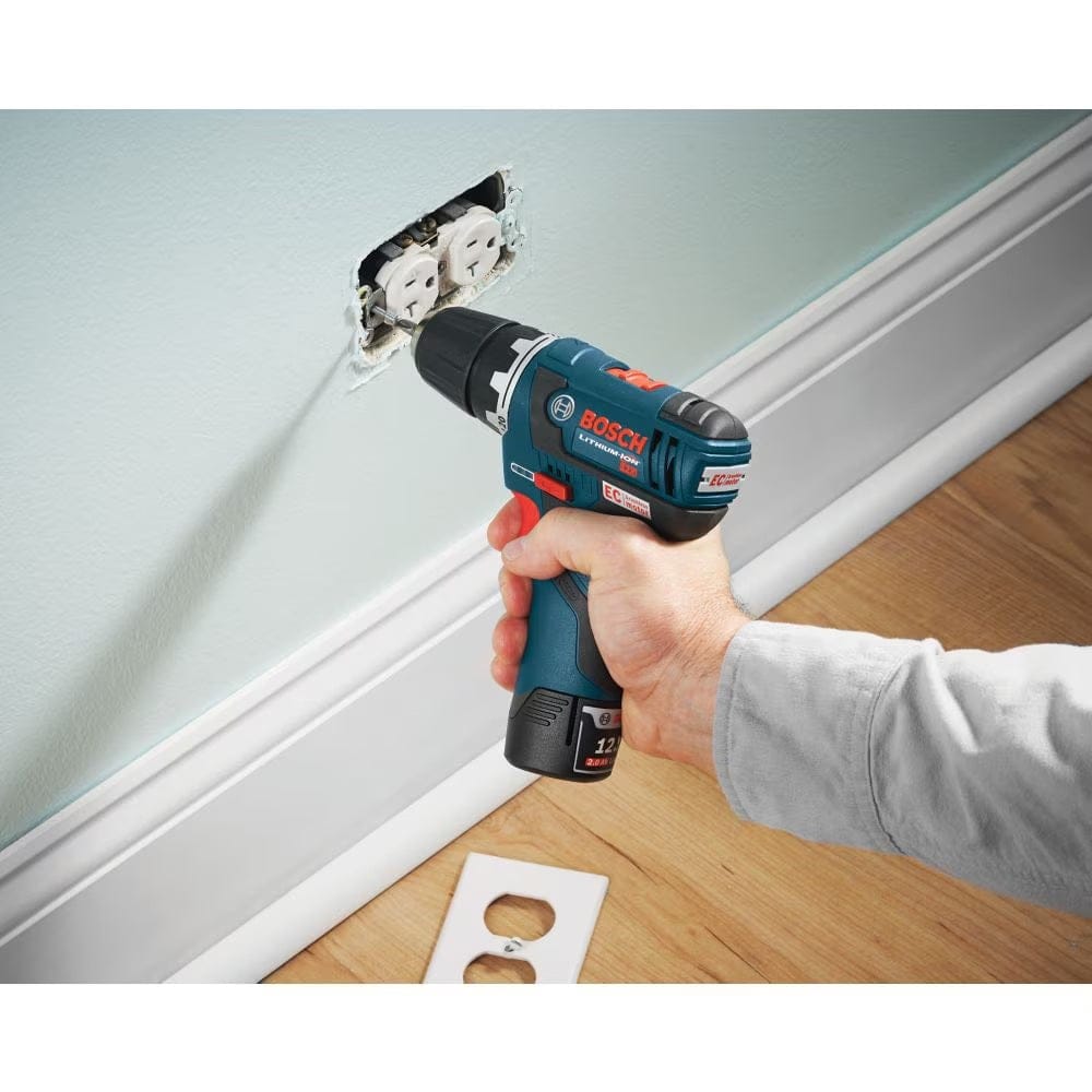 A technician using a cordless driver and a Phillips head bit from the Bosch MS4034 set to secure an electrical outlet into a wall box.