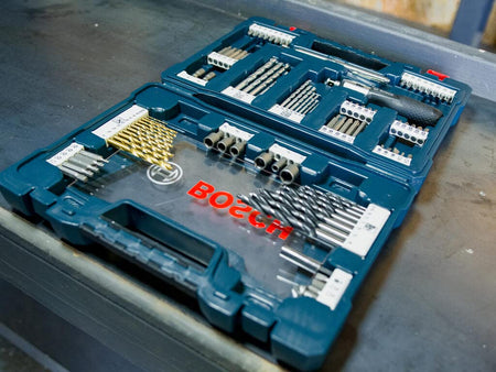 A real-world jobsite view of the Bosch 91-piece accessory set laid open on a metal workbench, demonstrating the easy accessibility of the various professional-grade bits during project execution.