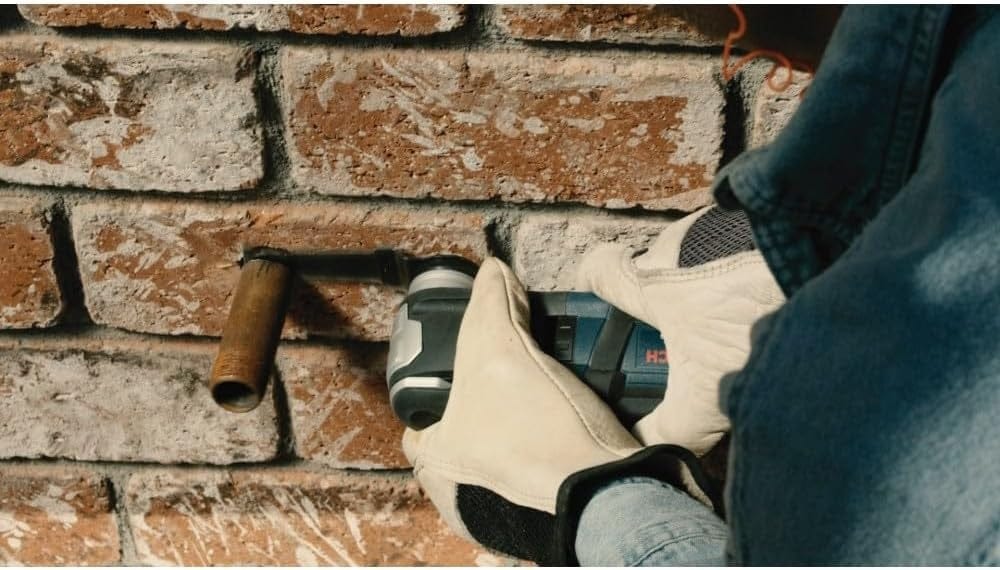 Action shot of the StarlockMax blade cutting a metal pipe flush against a red brick wall.