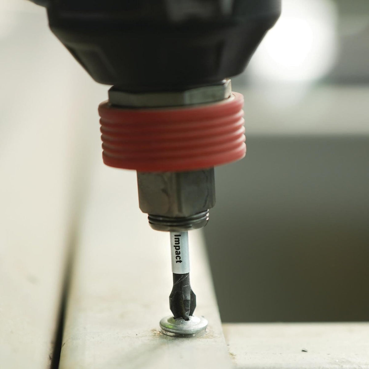 An extreme macro close-up view of the Bosch Impact Tough Phillips #2 bit point engaging a metal washer screw head, highlighting the silver high-visibility sleeve with the word impact clearly printed on it.
