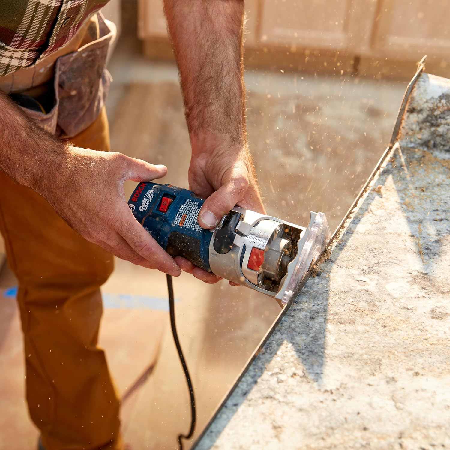 A professional using the router to trim the edge of a countertop material, showing the tool's control and stability during operation.
