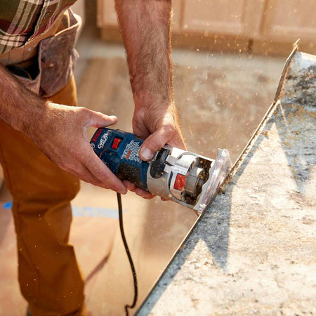 A professional using the router to trim the edge of a countertop material, showing the tool's control and stability during operation.