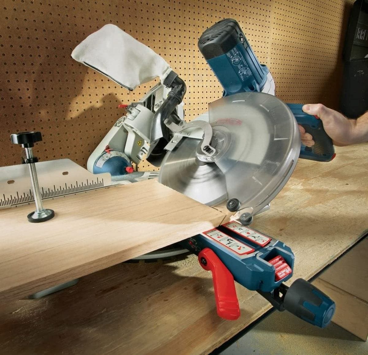 An action photo of a professional woodworker using a Bosch sliding compound miter saw equipped with an 80-tooth finishing blade to execute a clean, splinter-free crosscut on a large plywood panel.