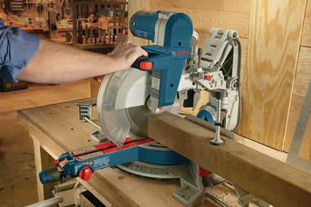 A workshop view demonstrating the stability and precision of the Bosch 12-inch circular saw blade as it crosscuts a heavy wood beam, showcasing the industrial-grade performance of the C4 Dyanite Carbide teeth.
